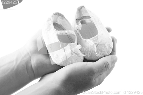 Image of Hands holding newborn baby shoes