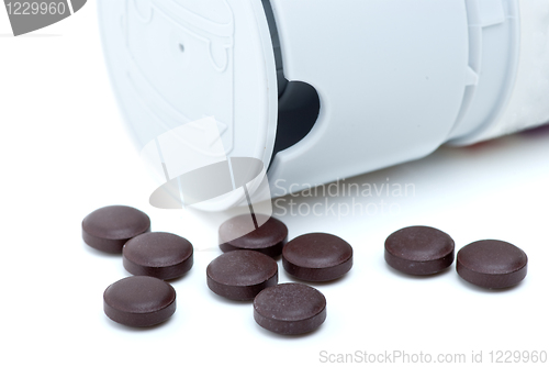 Image of Some brown pills near pill-dispenser