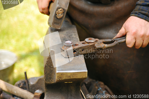 Image of Blacksmith hammering hot steel on anvil