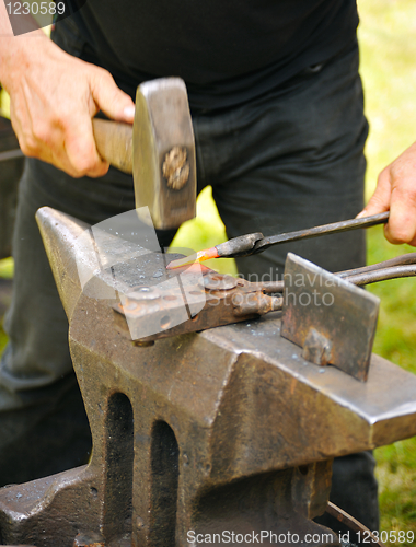 Image of Blacksmith hammering hot iron on anvil