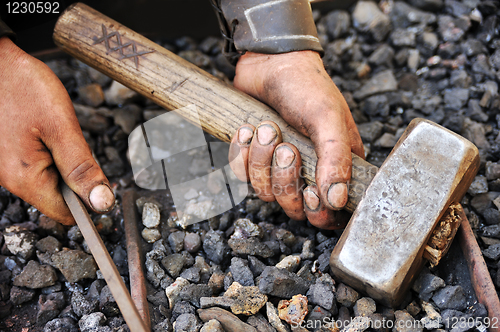 Image of Detail of dirty hands holding hammer and rod - blacksmith