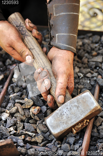 Image of Detail of dirty hands holding hammer - blacksmith