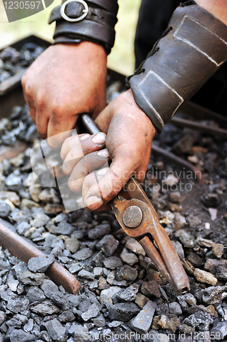 Image of Detail of dirty hands holding pliers - blacksmith