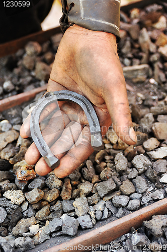Image of Detail of dirty hand holding horseshoe - blacksmith