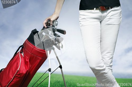 Image of Women standing by golf bag full of sticks 