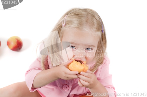 Image of Little girl eating peach in studio