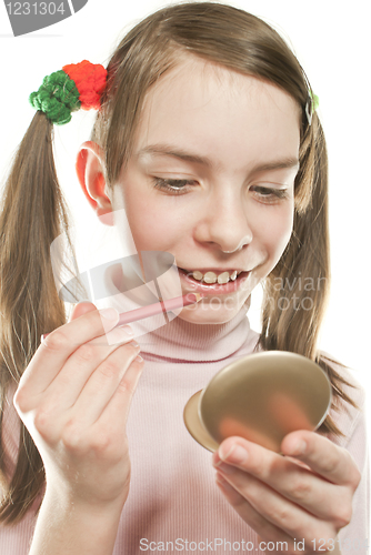 Image of Teen girl looking into mirror and making up lips