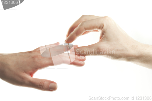 Image of Man's hand passing through the ring onto woman's finger