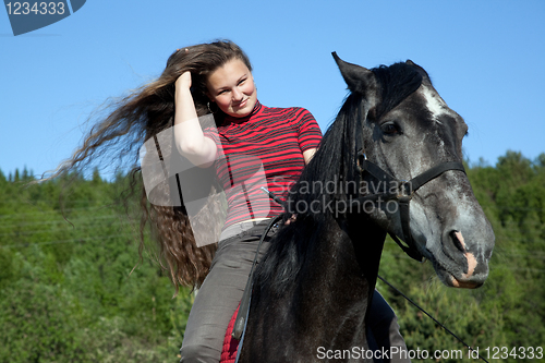 Image of A girl with flowing hair on a black horse