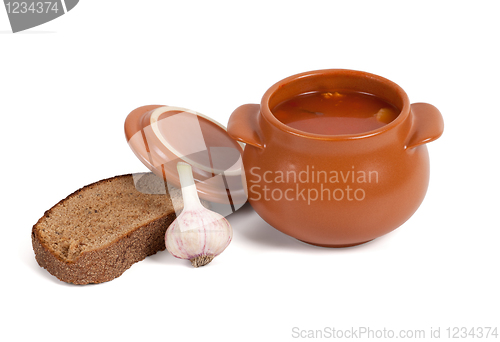 Image of Borsch in clay pot with bread and garlic
