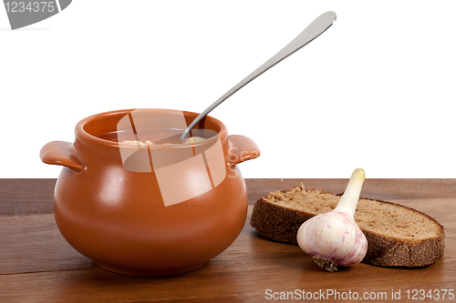 Image of Borsch in clay pot on wooden table