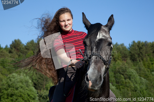 Image of Beautiful girl with brown hair on a black horse