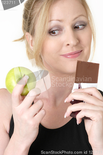 Image of woman deciding whether to eat apple or chocolate