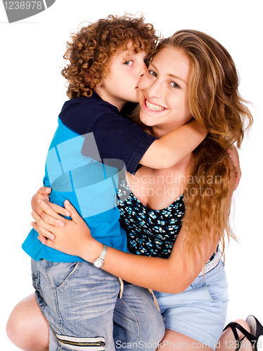 Image of Young kid kissing his mom and looking at camera