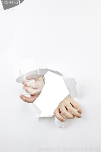 Image of Hands ripping through hole in paper