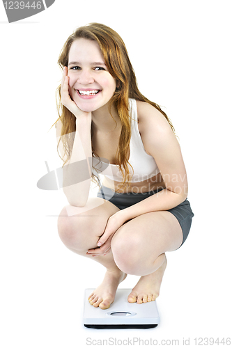 Image of Smiling young girl on bathroom scale