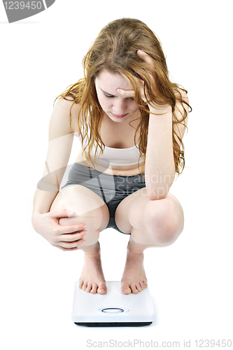 Image of Young girl on bathroom scale looking upset