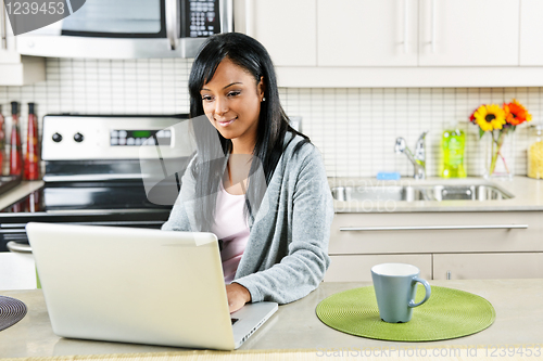 Image of Woman using computer in kitchen