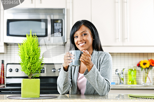 Image of Woman in kitchen with coffee cup