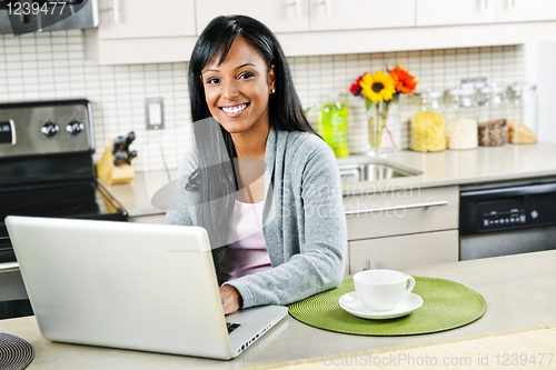 Image of Woman using computer in kitchen