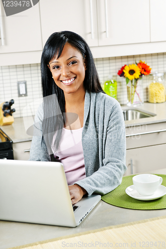 Image of Woman using computer in kitchen