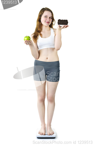 Image of Young girl on scale holding apple and cake