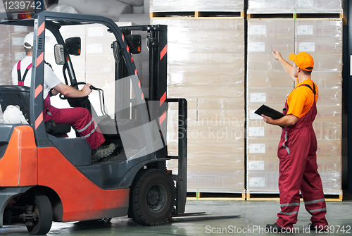 Image of warehouse works (forklift and workers)