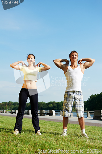 Image of Young man and woman doing stretching exercises