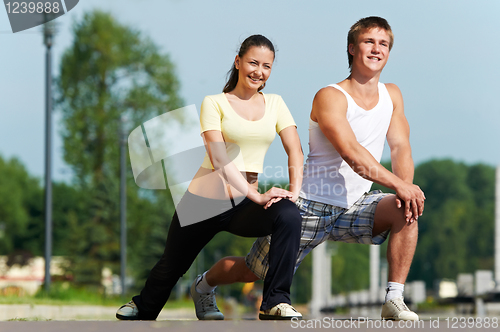 Image of Young man and woman doing stretching exercises