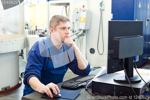 Image of worker operating CNC machine center