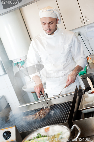 Image of chef frying beef steak on grill