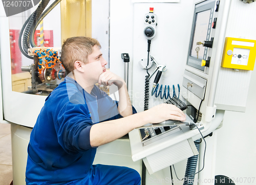 Image of worker operating CNC machine center