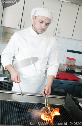 Image of chef frying beef steak on grill with fire