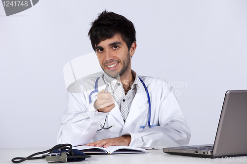 Image of frendly young doctor working with his laptop