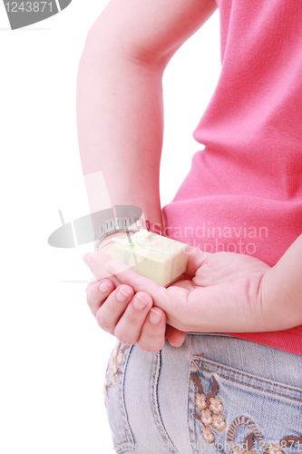 Image of Young woman with a gift behind her back isolated