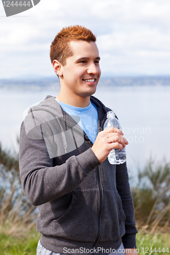 Image of Mixed race man holding water bottle