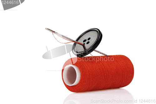 Image of red spool, black button and needle