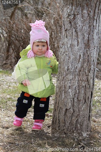 Image of girl hides behind a tree