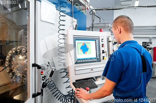 Image of worker operating CNC machine center