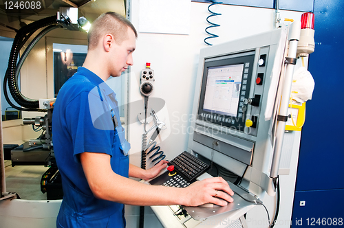 Image of worker operating CNC machine center