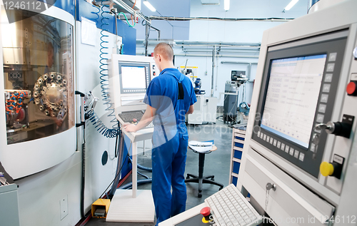 Image of worker operating CNC machine center