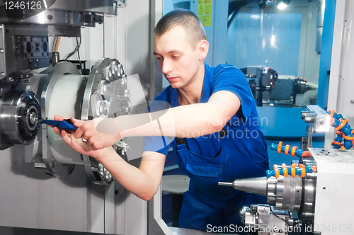 Image of worker operating CNC machine center