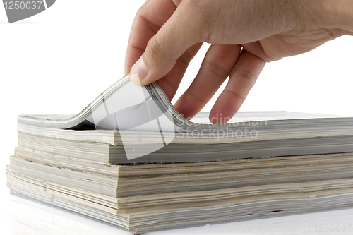 Image of hand browsing through stack of magazines