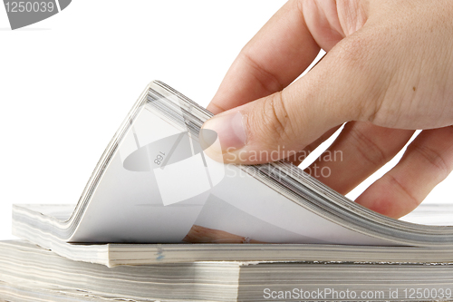 Image of hand browsing through stack of magazines