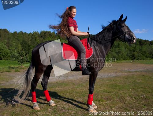 Image of Beautiful girl with brown hair on a black horse
