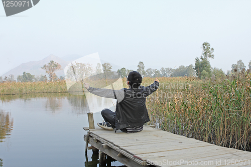 Image of Man resting on a pontoon by a lake 