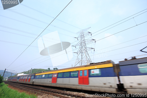 Image of passenger trains in motion and power tower on background 