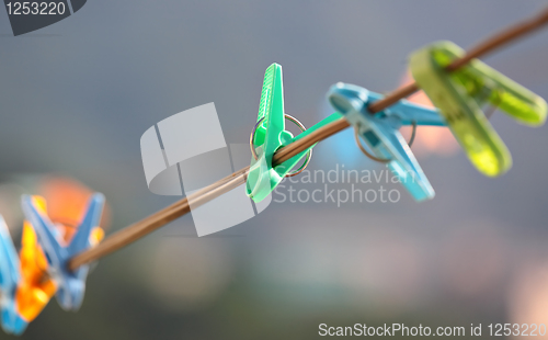 Image of Colorful clothes pegs hanging in wire