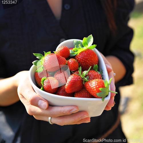 Image of strawberry in heart shape bowl with hand