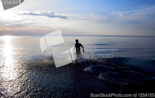 Image of Man standing in sea at late evening